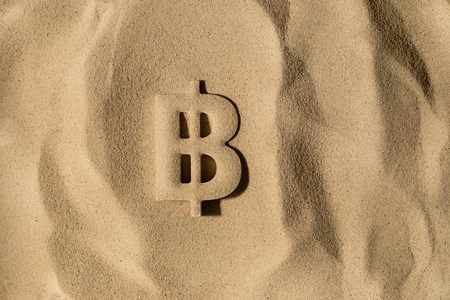 Bitcoin Symbol or Sign Covered with Sand in the Sun after Crisisの写真素材