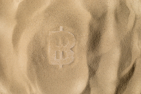 Bitcoin Symbol or Sign Covered with Sand in the Sun after Crisisの写真素材
