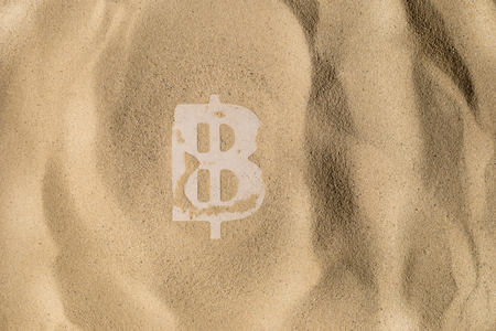 Bitcoin Symbol lies on the Sand in Direct Sunlightの写真素材