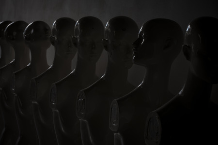 Plastic Woman Mannequins Standing in The Line, With One Looking to Another Direction then the Others in Dark and Sad Atmosphere.の写真素材