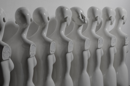 White Woman Torso Mannequins Standing in The Line All Looking to Same Direction except of One, all shoot In Grey Depressive Moodの写真素材