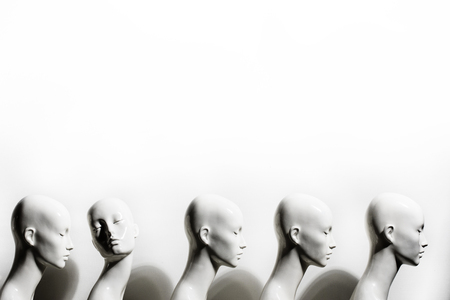 High Key Photo of Plastic Woman Figurines Standing in The Line, With One Looking to Another Direction then the Others on White Backgroundの写真素材