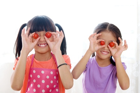 Asian girls posing with cherry tomatoesの写真素材