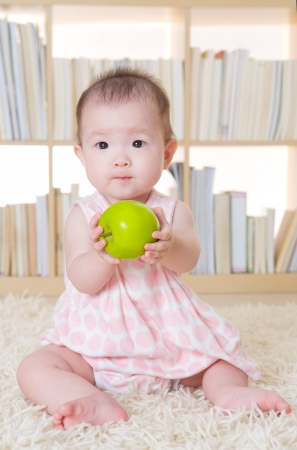 baby girl holding an appleの写真素材