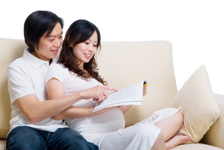 Asian pregnant woman reading magazine together with husbandの写真素材