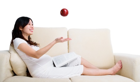 Lovely asian pregnant woman throwing an apple upwardの写真素材