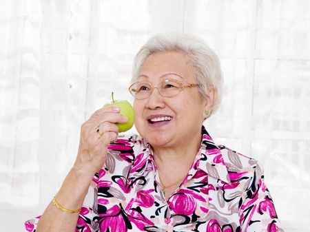 Asian senior woman eating an appleの写真素材