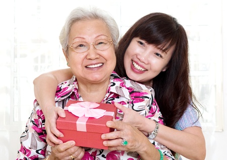 Asian senior woman receiving gift from daughterの写真素材