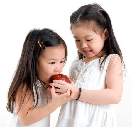 cute asian girls sharing an appleの写真素材