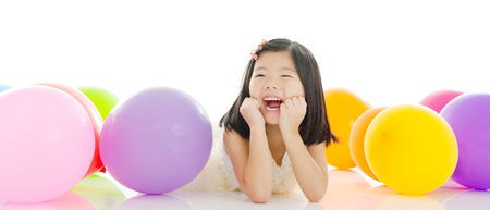 Cheerful asian kid lying on the floor with balloonsの写真素材