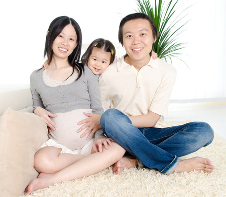 Asian man putting his hand on his pregnant wife\'s stomachの写真素材