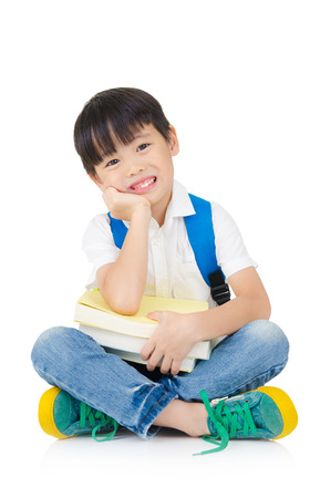 Asian preschool boy with schoolbag and books sitting on the floorの写真素材