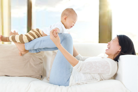 Asian mother lifting up her baby with legsの写真素材