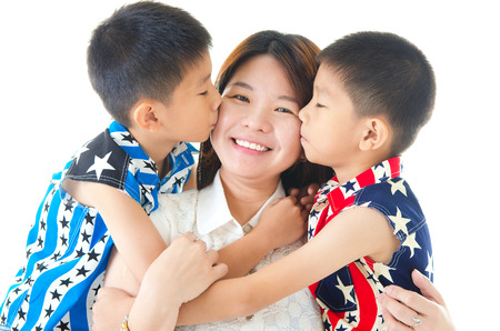 Asian mother kissed by her twin sonsの写真素材