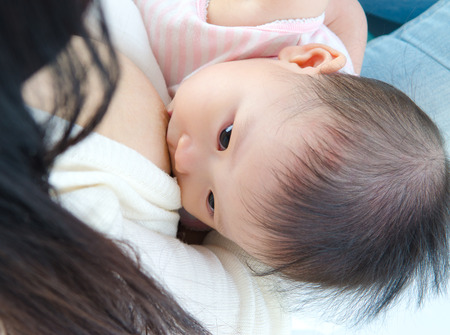 Six months old asian baby drinking breastmilkの写真素材
