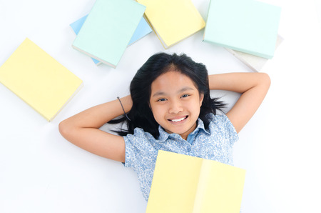 Asian child lying on the floor with booksの写真素材