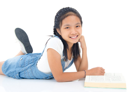 Asian girl lying on the floor and reading a bookの写真素材