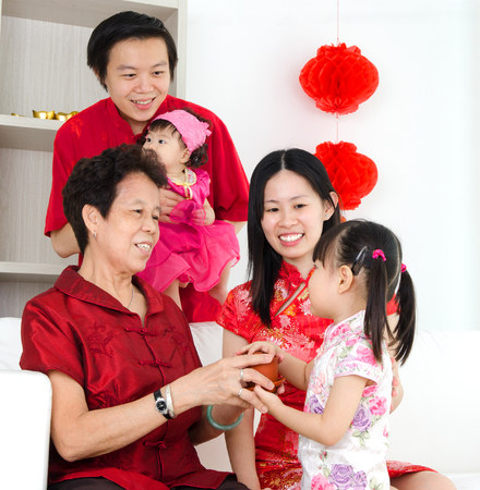 Asian girl presenting tea to grandmother during chinese new yearの写真素材