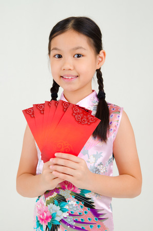 Asian girl in traditional chinese costume, cheongsam holding red packet. Chinese new year concept.の写真素材