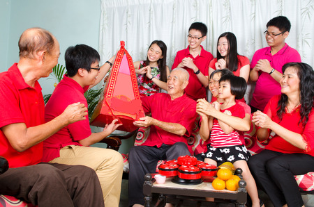 Grandson presenting gift hamper to grandfather on chinese new year.の写真素材