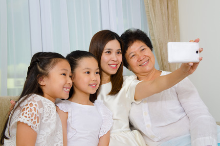 Asian three generations family taking photo of themselves using handphoneの写真素材