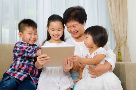 Asian senior woman and grandchildren having fun with tablet computerの写真素材