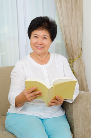 Indoor portrait of asian senior woman reading bookの写真素材