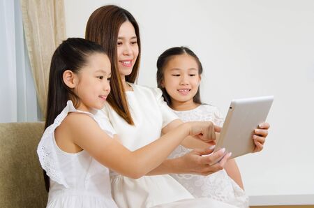 Asian woman and daughters using tablet computerの写真素材
