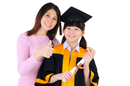 Asian girl in graduation gown and mortarboard together with motherの写真素材