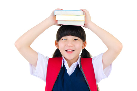 Cheerful asian primary student put books on her headの写真素材