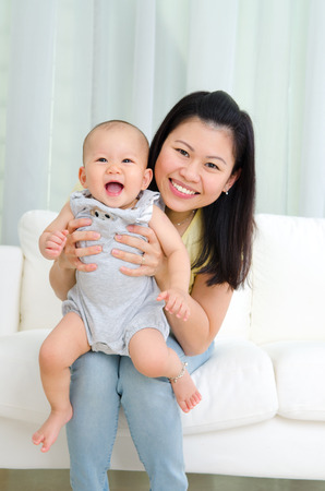 Indoor portrait of asian mother and her cheerful babyの写真素材