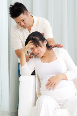 Asian man taking care of his pregnant wife who suffer body painの写真素材
