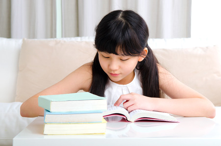 Beautiful asian girl reading book at homeの写真素材