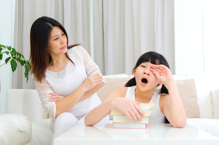Asian mother looking at her sleepy daughterの写真素材
