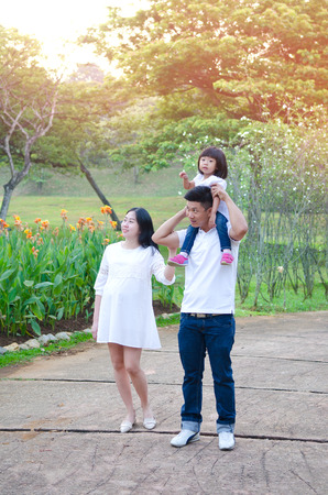 Asian pregnant woman walking in the park together with husband and daughterの写真素材