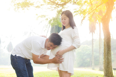 Asian man listening to his pregnant wife's stomachの写真素材