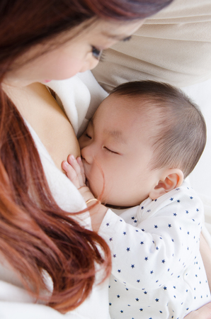 Six months old asian baby drinking breastmilkの写真素材