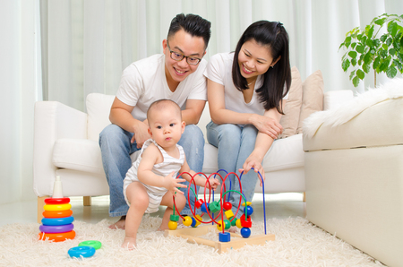 Asian parent looking at their baby playing toy in the living roomの写真素材