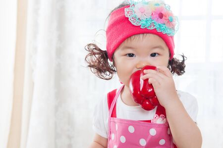 Little asian child biting a capsicumの写真素材