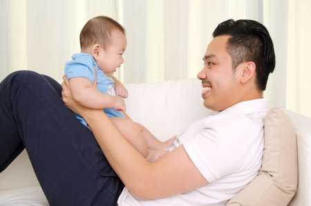 Asian father playing with his baby at homeの写真素材