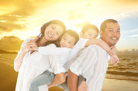 Asian family relaxed at beachside in the beautiful sunsetの写真素材