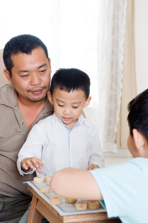 Asian man playing chinese chess with kidsの写真素材
