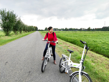 Asian woman riding bicycle on the road and looking at the greenfieldの写真素材