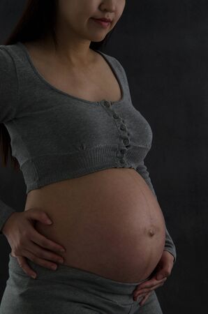 Portrait of asian pregnant woman. Low Light setting.の写真素材