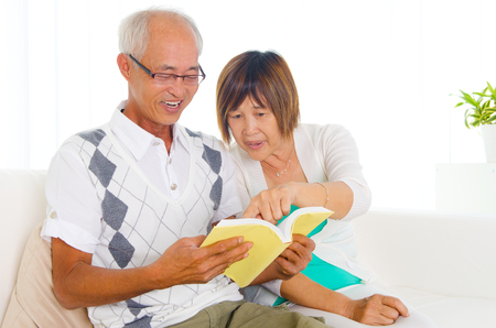 Asian senior couple reading at homeの写真素材