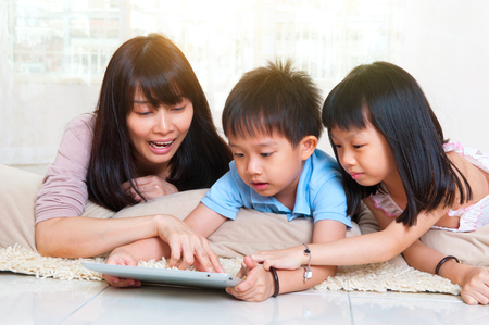 Asian mother and kids having fun with tablet computerの写真素材