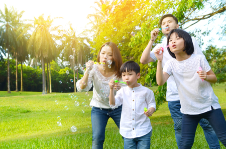 Asian family blowing bubbles in the parkの写真素材