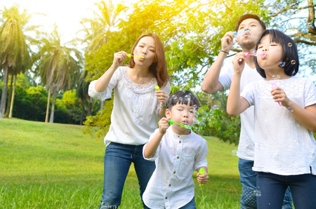 Asian family blowing bubbles in the parkの写真素材