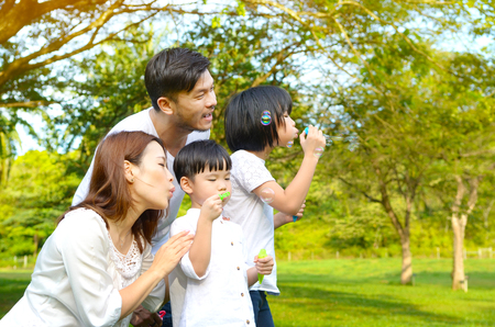 Asian family blowing bubbles in the parkの写真素材