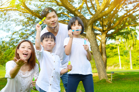 Happy asian family blowing bubbles in the parkの写真素材